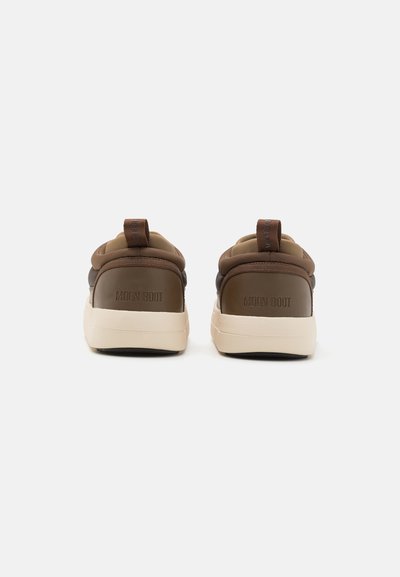Brune skinn lav-top sneakers med beige såle, med en glatt tekstur, polstret krage og liten løftestropp bak.