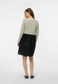 Svītrains garām piedurknēm tops krēmkrāsā un melnā krāsā, saskaņots ar melnu svārku. Mīksta auduma, ar brīvu siluetu. Melnas apdrukātas dzīvokļa kurpes.