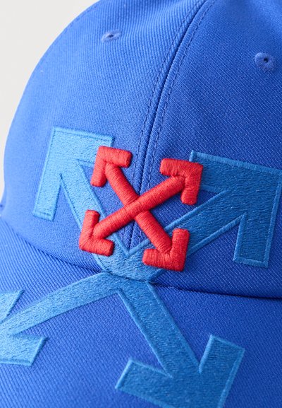 Casquette en tissu bleu avec des flèches brodées qui se chevauchent : quatre flèches rouges croisées au centre sur le devant, de plus grandes flèches bleues en arrière-plan.