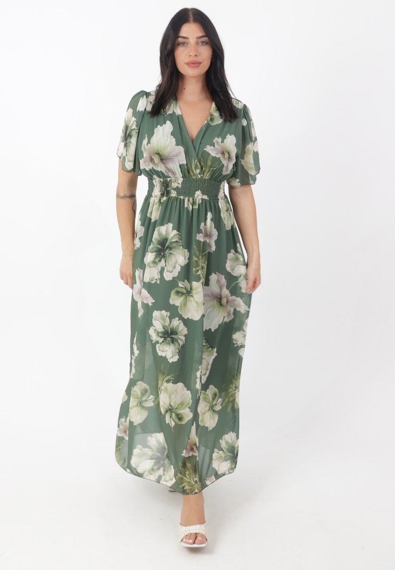 Robe maxi en tissu vert avec un grand motif floral en blanc et rose clair. Présente un décolleté en V, des manches ballon et une taille smockée.