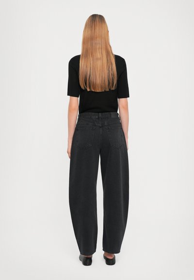 Black denim wide-leg jeans with a high waist, featuring two back pockets and frayed hem. Paired with a black short-sleeve top.