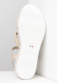 Sandalo in pelle beige con dettaglio intrecciato, dotato di una suola in gomma bianca. Contrassegnato con "NeroGiardini" e taglia 37, prodotto in Italia.