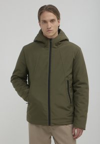 Olivgrünes, kapuzenähnliches Jacket mit einem Reißverschluss vorne und seitlichen Taschen; hat eine glatte, matte Textur und eine taillierte Passform.