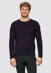 Langsleeve shirt met ronde hals in dieppaarse kleur, gemaakt van een gestructureerde stof, gedragen met zwarte broek, met minimale stikseldetails.