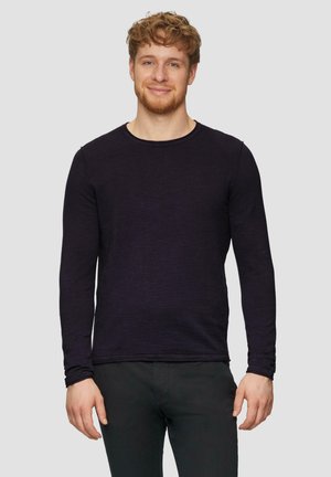 Langsleeve shirt met ronde hals in dieppaarse kleur, gemaakt van een gestructureerde stof, gedragen met zwarte broek, met minimale stikseldetails.