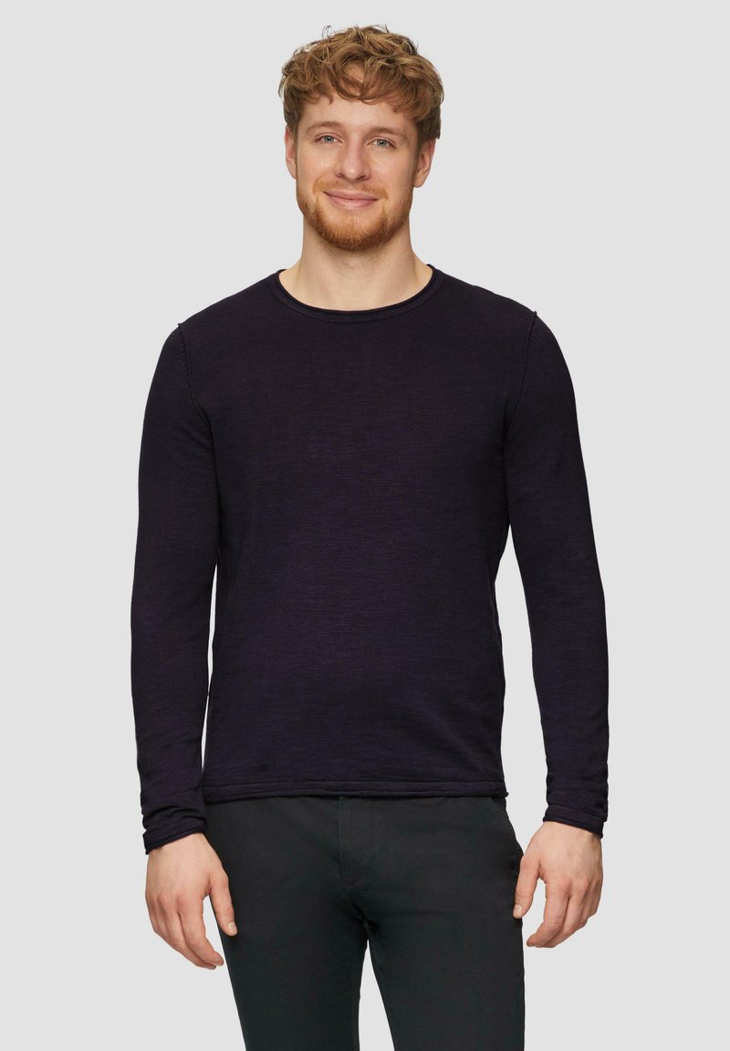 Langsleeve shirt met ronde hals in dieppaarse kleur, gemaakt van een gestructureerde stof, gedragen met zwarte broek, met minimale stikseldetails.