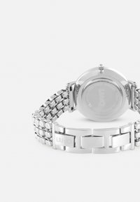 Sølvmetal ur med et kædedesign, rundt urkasse, minimalistisk urskive og en lås med mærket "LIU·JO" indgraveret.
