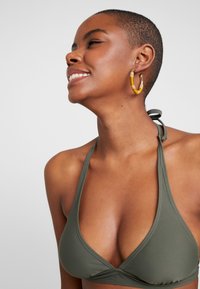 Olivgrüner, dreieckiger Bikini-Oberteil mit Halterneck-Bindungen, aus Schwimmmaterial gefertigt, mit sauberem Nähen für einen sicheren Sitz.
