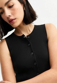 Zwarte geribbelde tanktop met een ronde halslijn en vijf zwarte knopen aan de voorkant. Gladde textuur en mouwloos ontwerp.