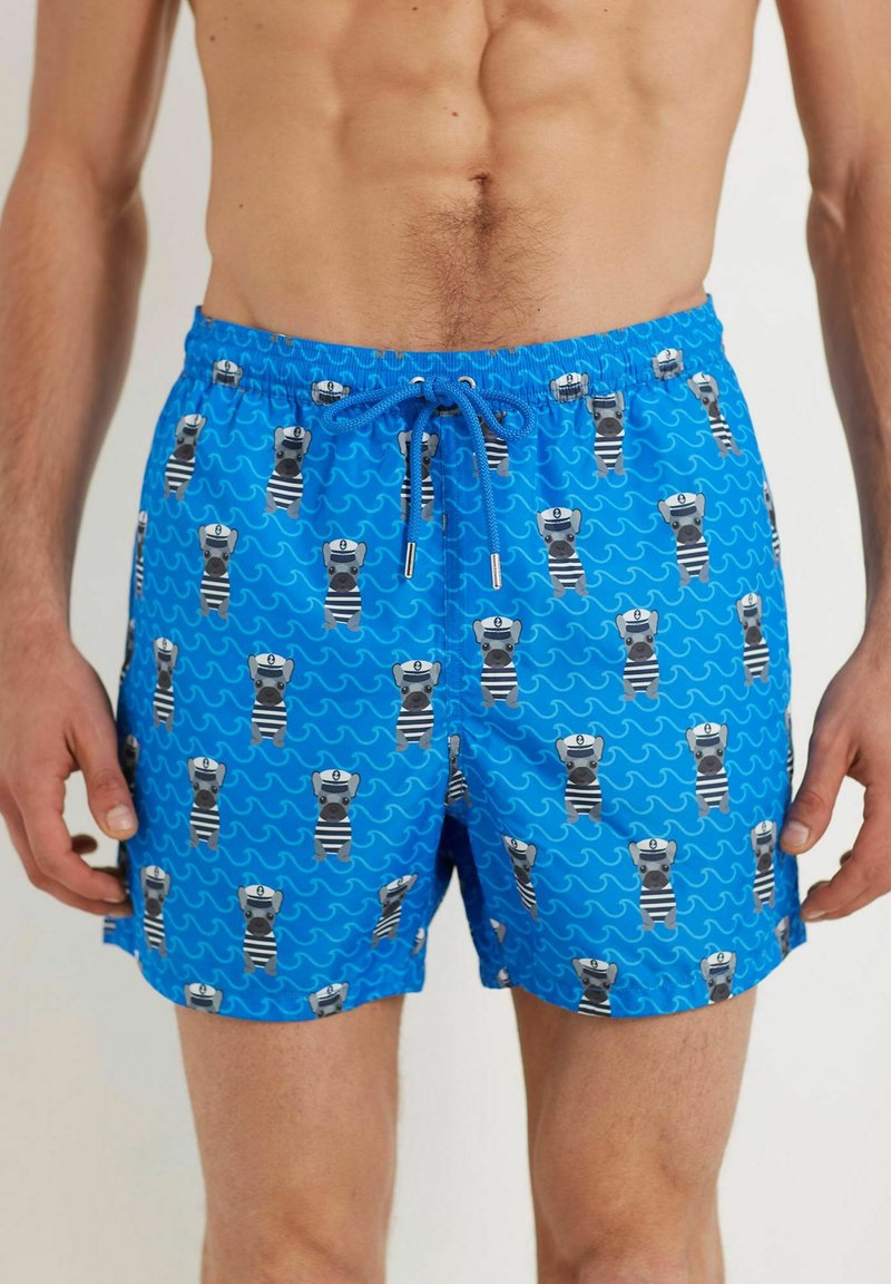 Pantaloni scurți de înot albaștri cu un model jucăuș de urși cartoon îmbrăcați în costume de marinar, cu talie cu șnur și buzunare laterale. Textură de țesătură netedă.