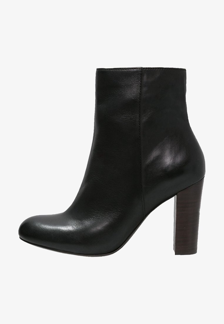 Bottine en cuir noir avec bout rond et talon haut en bois empilé.