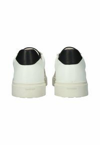 Bílé kožené tenisky s černým koženým akcentem na patě a béžovou podrážkou, s embosovaným logem "BLACKSTONE" na patě.