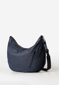 Grande borsa a tracolla a forma di mezzaluna di colore blu navy, con cinturino regolabile e numerosi compartimenti con zip, su uno sfondo bianco.