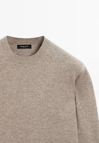 Maglione grigio chiaro con collo rotondo e polsini a costine, realizzato in un tessuto morbido con una texture liscia. Presenta un'etichetta del brand all'interno del colletto.