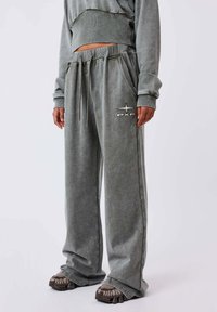 Grijze, oversized sweatpants met zijzakken, een trekkoord taille en een geborduurd logo op de dij. Gemaakt van zachte, gestructureerde stof.