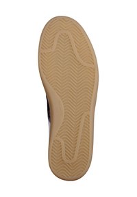 Widok od spodu podeszwy buta z fakturowanym, falistym wzorem w jasno-beżowej gumie, z gładką krawędzią i małym logiem.