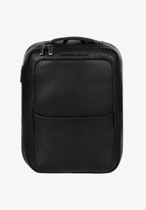 Mochila de cuero negro con una textura suave, que cuenta con un bolsillo frontal, un asa superior y acentos de hardware plateado. Diseño simple y rectangular.