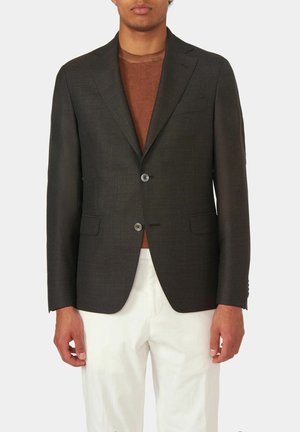 Dunkelgrauer, taillierter Blazer mit Revers, zwei Knöpfen und seitlichen Taschen. Über einem braunen Pullover getragen und mit weißen Hosen kombiniert.