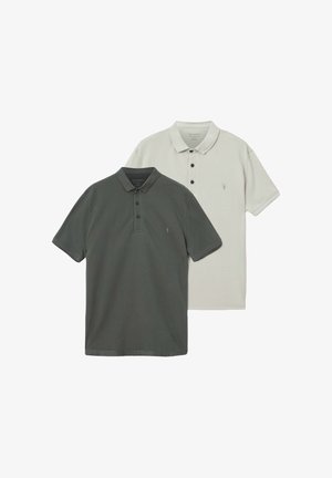 Due polo piegate, una grigio scuro e una bianco sporco, ciascuna con tre bottoni e un piccolo logo ricamato sul petto.