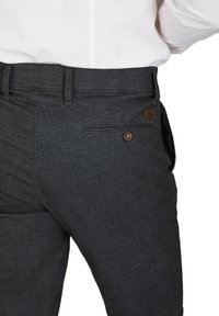 Dunkelgraue Hosen aus strukturiertem Stoff mit einem Knopfverschluss und einer Gesäßtasche mit einem Lederetikett. Der Bund ist mit Gürtelschlaufen versehen.