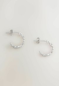 Cercei din argint, cu un design texturat și ciocănit. Acestea au o formă circulară clasică și se prind cu un sistem de închidere cu tijă.