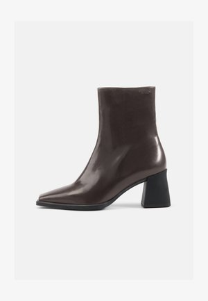 Braune Lederstiefelette mit spitzer Zehenpartie und einem klobigen schwarzen Absatz. Glatte Textur, minimalistisches Design und keine sichtbaren Verzierungen.
