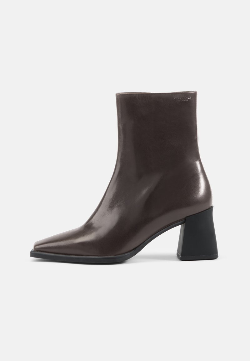 Stivaletto in pelle marrone con punta affusolata e tacco spesso nero. Texture liscia, design minimalista e senza adornamenti visibili.