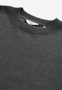Dark grey sweatshirt made of soft, textured fabric. Features a ribbed crew neckline and tag label inside. Simple, unadorned design.