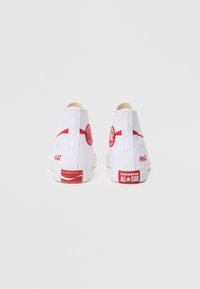 Λευκά ψηλά αθλητικά παπούτσια με κόκκινες λεπτομέρειες, με κυκλικό λογότυπο και τη σήμανση "Converse All-Star" στη φτέρνα. Επάνω μέρος από καμβά, λαστιχένια σόλα.