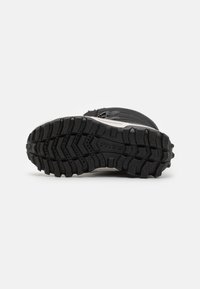 Bota de senderismo negra con suela texturizada, patrón de tracción prominente y cierre con cremallera. Diseñada para ofrecer tracción y estabilidad en terrenos variados.