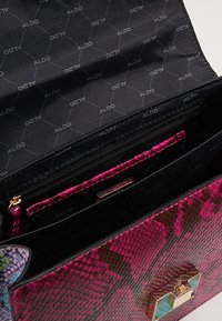 Borsa rosa effetto pelle di serpente con chiusura in metallo dorato e interno nero con il marchio ALDO. Include più scomparti per l'organizzazione.