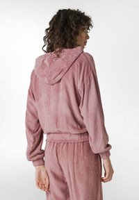 Sudadera de pana rosa con un bolsillo frontal y cordón, que presenta una textura acanalada, puños elásticos y un corte relajado.