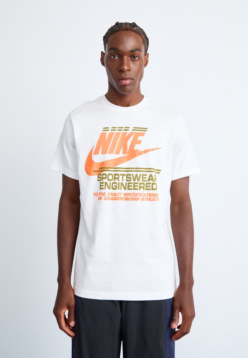 Hvid bomulds T-shirt med et stort multicolor Nike-logo med grøn og orange tekst, korte ærmer og rund hals.