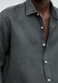 Dark gray linen shirt with a collar, displaying a relaxed fit, front button closure, and subtle texture. Features white buttons.