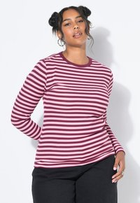 T-shirt ajusté à manches longues, orné de rayures horizontales en rouge foncé et rose clair. Encolure ronde et texture côtelée. Pantalons noirs portés en dessous.