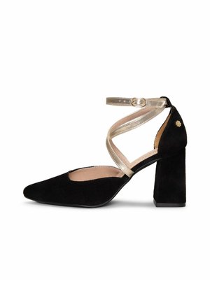 Zapato de tacón grueso de ante negro con punta puntiaguda y tiras metálicas doradas que se cruzan en el tobillo con cierre de hebilla.