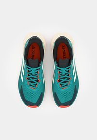 Miętowe buty do biegania z białymi paskami, pomarańczowymi akcentami i fakturowanym wierzchem. Posiadają amortyzowaną podeszwę oraz oddychający siateczkowy design.