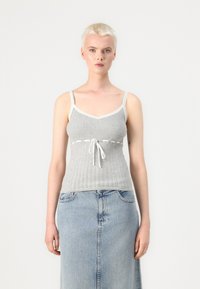 Haut en tricot gris à côtes avec dentelle, présentant un lien à l'avant et une coupe ajustée, associé à une jupe en denim clair.