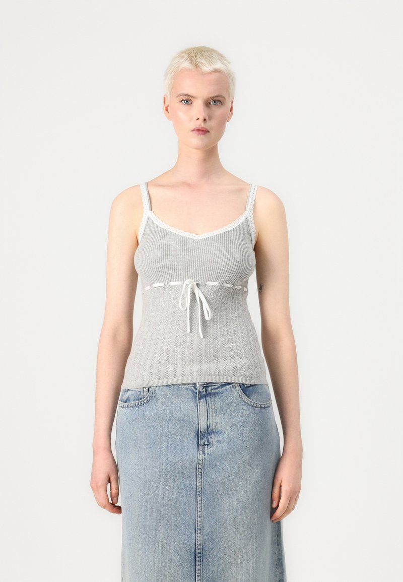 Haut en tricot gris à côtes avec dentelle, présentant un lien à l'avant et une coupe ajustée, associé à une jupe en denim clair.