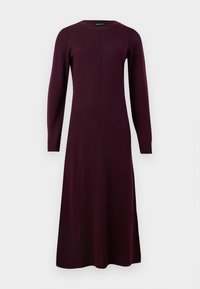 Robe en tricot à manches longues, ajustée, en bordeaux profond. Encolure ronde, texture lisse et longueur midi, avec une silhouette simple et épurée.
