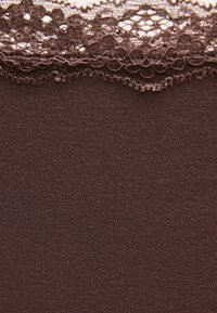 Καφέ ύφασμα με λεπτή δαντελωτή φλοράλ διακόσμηση στην κορυφαία άκρη, που δείχνει λεπτή υφή και περίπλοκη λεπτομέρεια δαντέλας.