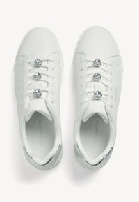 Sneaker bianchi con una finitura in pelle liscia, caratterizzati da tre decorazioni metalliche a forma di cuore sulle stringhe e dettagli argentati sul tallone.