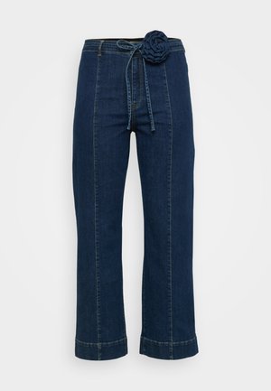 Mørkeblå denim bukser med vide ben, blomstrete stoffdetaljer i livet og snor i midjen. Distinktiv stikking og avskåret søm.