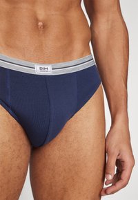 Marineblaue Baumwollslips mit einem grauen gestreiften elastischen Bund. Sie haben eine taillierte Passform und eine glatte Textur, ideal für den täglichen Gebrauch.