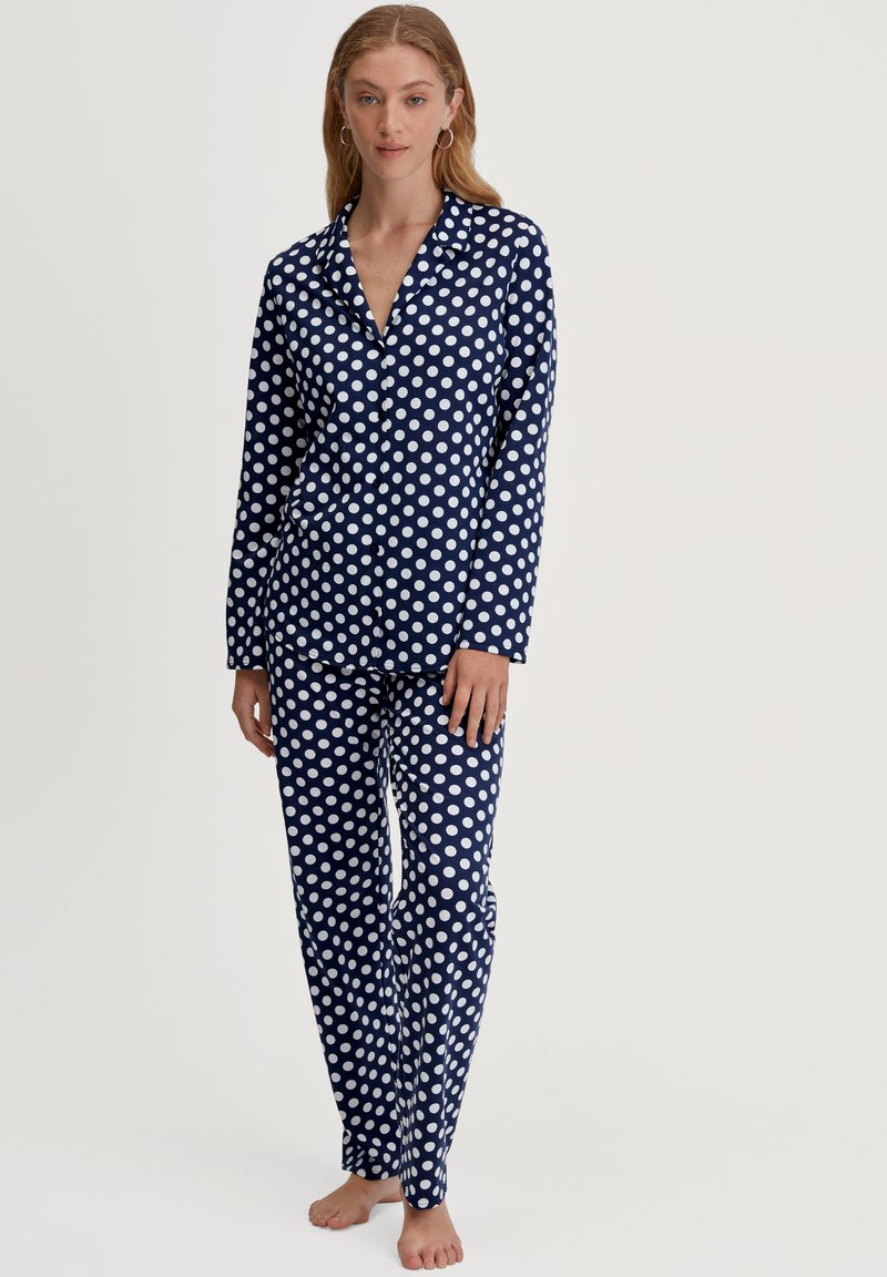 Navy pyjama set met witte stippen, bestaande uit een colbert met knopen en bijpassende lange broek, gemaakt van zacht, lichtgewicht materiaal.