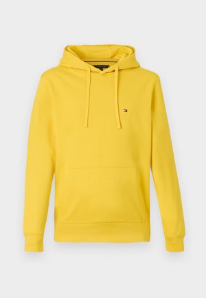 Żółta bluza z długim rękawem z przednią kieszenią kangurką, z kapturem na sznurki i małym logo flagi Tommy Hilfiger na lewej piersi.