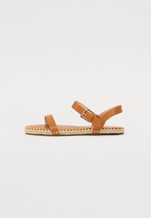 Sandales en cuir avec un dessus marron, une bride de cheville réglable et une semelle en jute tressé. Présente un design simple avec des accents matériels minimalistes.