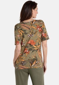 Groene bloemen t-shirt met korte mouwen, voorzien van oranje en crèmekleurige patronen, met een ronde halslijn en een losse pasvorm.