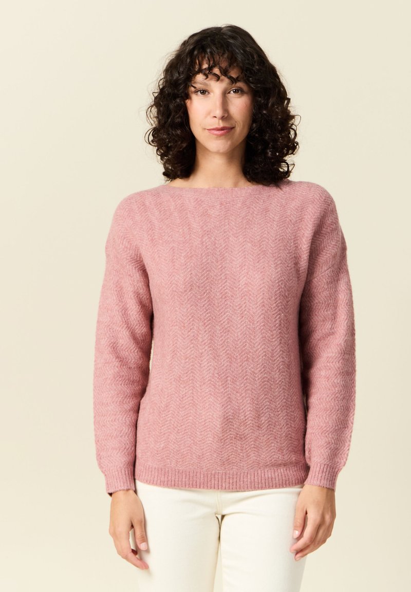 Rosa sweater med fiskbensmönster, rund halsringning och långa ärmar, tillverkad av mjukt texturerat material, tillsammans med vita byxor.