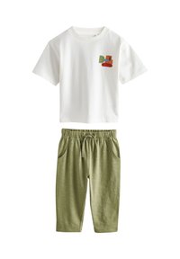 Fehér póló, amelynek mellrészén színes építőipari jármű grafika látható, zöld, elasztikus derékpántos nadrággal, oldalra zsebekkel.